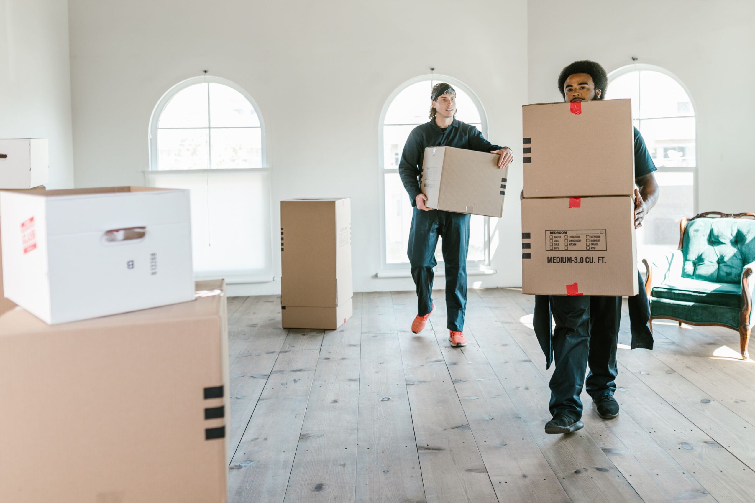 service-1 Two movers carrying boxes in a sunlit room, ready to assist with relocation.